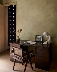 a desk with a chair and vase on it in front of a wall mounted wine rack