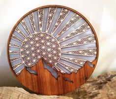 a wooden plate with an intricate design on the front and sides, sitting on top of a pile of wood logs