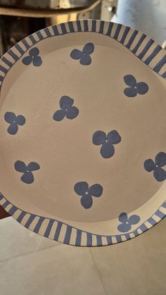 a blue and white flowered dish is held up by someone's hand on the table