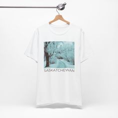 Hey there! We hope you like our Saskatchewan Winter T-Shirt! It's available in multiple colors, including white, soft cream, pink, asphalt, and baby blue, and comes in sizes S-3XL.  The best part? These shirts are designed, printed, and shipped from Canada, so you can show off your love for this great country while supporting local businesses.  Made with 100% Airlume combed and ring-spun cotton, these shirts are not only lightweight and breathable but also perfect for both active and leisure wea Pre-shrunk White Band Merch Top, White Pre-shrunk Band Merch Top, White Relaxed Fit Shirt With Band Merch, Vintage White T-shirt With Text Print, White Band Merch Shirt With Screen Print, White Screen Print Band Merch Shirt, White Cotton Band Merch Shirt, Vintage White Shirt With Text Print, White Shirt With Band Merch Printing