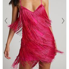 a woman is wearing a pink dress with feathers on it