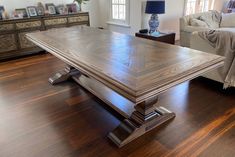 a large wooden table sitting on top of a hard wood floor next to a couch