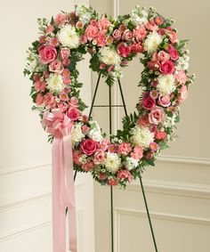 a heart shaped wreath with pink and white flowers