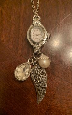 a close up of a watch on a table with an angel charm attached to it