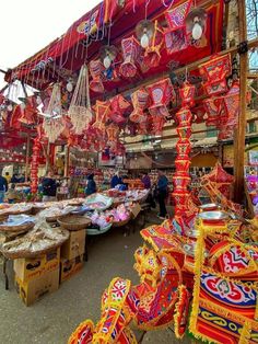 an outdoor market with lots of colorful decorations and lights hanging from it's ceiling