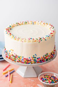 a white cake with sprinkles on it sitting on top of a table