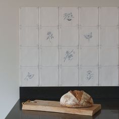 a loaf of bread sitting on top of a wooden cutting board next to a white tile wall