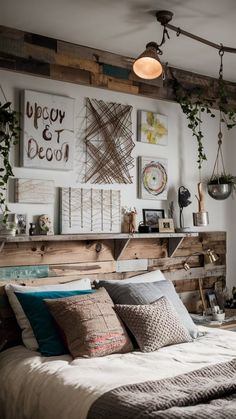 a bed with lots of pillows and pictures on the wall above it, along with hanging plants