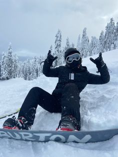 a snowboarder is sitting in the snow with his feet up and arms out