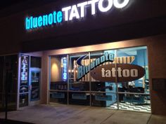 a blue note tattoo store front at night