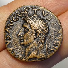 an ancient roman coin is being held in someone's hand, with the image of a man on it