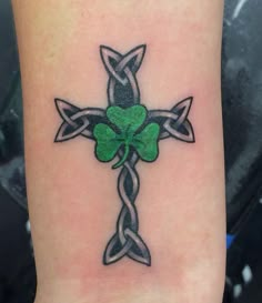 a tattoo with a cross and shamrock leaves on it