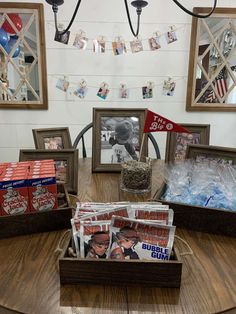 the table is covered with magazines and other items for sale in front of two framed pictures