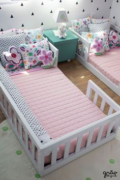 two twin beds with pink sheets and pillows in a child's room, one has a teddy bear on the bed