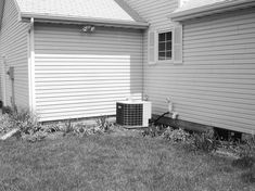 an air conditioner sitting on the side of a house in front of a garage