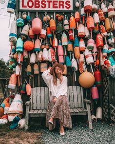 a woman sitting on a bench in front of a store with lots of lobsters