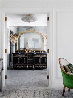 an elegant bathroom with black and gold accents, marble countertops and green velvet chair