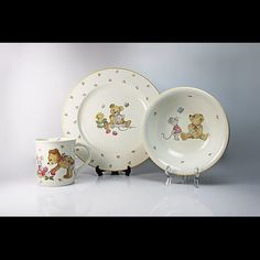 three plates and two cups with teddy bears on them, one is holding a bear