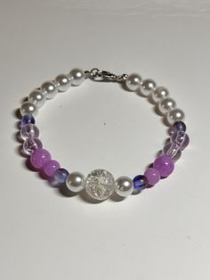 "This is a handmade beaded bracelet with  purple/pink and white fashion colors -   Would fit a 6.5\" - 7\" when stretched.   The silver with the white pearl color beads make this really an eye catching statement piece! Picture taken in different lighting to show how it looks under different settings and lighting. We offer free shipping on all of our items! If you are interested in a certain color combination, please send me a private message to see if we have your desired colors in stock. Thank Cheap Purple Bracelets With Tiny Beads, Purple Beaded Pearl Bracelets, Purple Pearl Bracelet As A Gift, Handmade White Pearl Crystal Bracelet, Purple Beaded Pearl Bracelet Gift, Purple Beaded Pearl Bracelet For Gift, Purple Beaded Pearl Bracelet As Gift, Purple Stretch Bracelet With Colorful Beads, Purple Beaded Pearl Bracelet With Round Beads