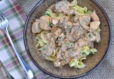 a bowl filled with pasta and meat on top of a table next to a fork