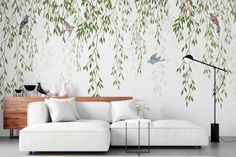 a living room with white furniture and green leaves on the wall, including a couch