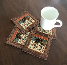 four square coasters on a wooden table with a coffee cup in front of them