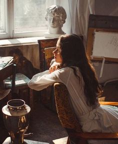 a woman sitting in a chair next to a window