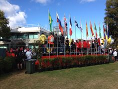 a group of people standing on top of a lush green field next to tall flags