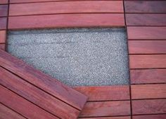 a close up view of a wooden decking area with concrete and wood slats