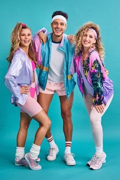 three young people posing for a photo in front of a blue background with one man wearing pink