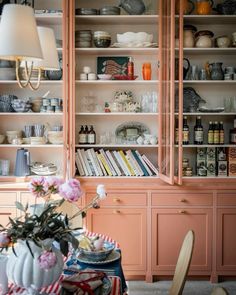 a dining room filled with lots of furniture and shelves full of dishes on top of them