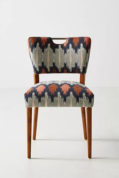 an upholstered chair with wooden legs and patterned fabric