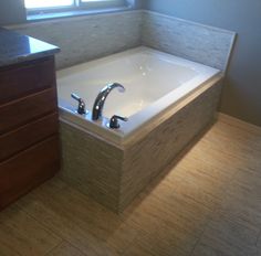 a bath tub sitting next to a wooden cabinet in a bathroom with tile flooring