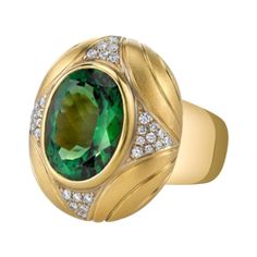 A vibrant, rich green 10.31 carat tourmaline oval is featured in this gorgeous, custom-designed 18k yellow gold ring. The tourmaline is a gem in every respect, possessing exceptional color, excellent clarity and a beautiful cut. This regal-looking ring was designed especially to showcase this magnificent gemstone and combines an elegant brushed finish with high-polished detail to complement and contrast the wide, rounded high-polished band. Thirty-six sparkling round brilliant cut white diamonds Wide Diamond Bands, Dome Rings, Rubellite Tourmaline, Green Rings, Dome Ring, Gold Engraving, Rich Green, 18k Yellow Gold Ring, Design Earrings