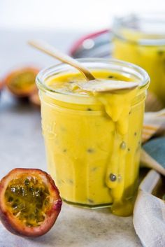 a jar filled with yellow liquid sitting on top of a table next to a piece of fruit