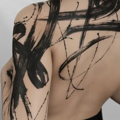 the back of a man's body with black ink on it and an abstract design