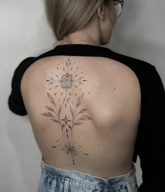 the back of a woman's shoulder with a flower tattoo on it