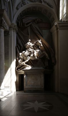 a statue in the middle of a room with sunlight coming through it's windows