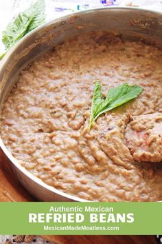 mexican refried beans in a large pot on a cutting board with fresh basil leaves