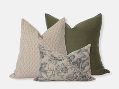 three pillows with different designs on them, one in green and the other in beige