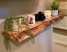 a wooden shelf with mugs and plants on it