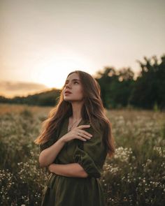 a woman standing in a field with her arms crossed