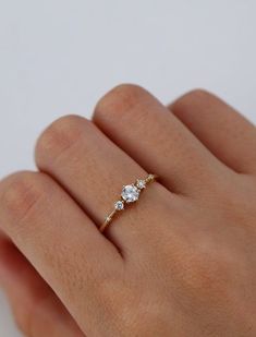 a woman's hand with a diamond ring on top of her finger and the other hand holding it