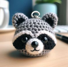 a crocheted raccoon keychain sitting on top of a desk