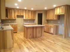 an empty kitchen with wooden floors and cabinets