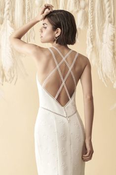 a woman in a white wedding dress with feathers hanging from the ceiling behind her back