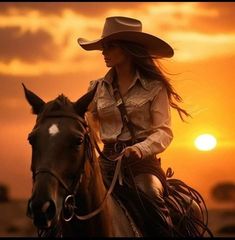 a woman riding on the back of a brown horse at sun sets in the background