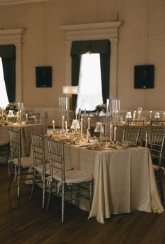 the tables are set up with white linens and gold place settings for an elegant dinner