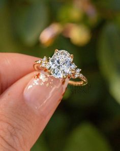 a woman's hand holding an engagement ring with two diamonds on it and the other side