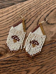 the beaded earrings are made with white and brown beads, which have a face on it